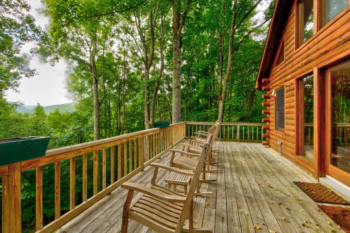 A peaceful wooden deck with classic rocking chairs overlooking the hillside and nestled among surrounding trees. The deck creates an inviting spot for relaxing, socializing, or watching local wildlife in a tranquil setting.