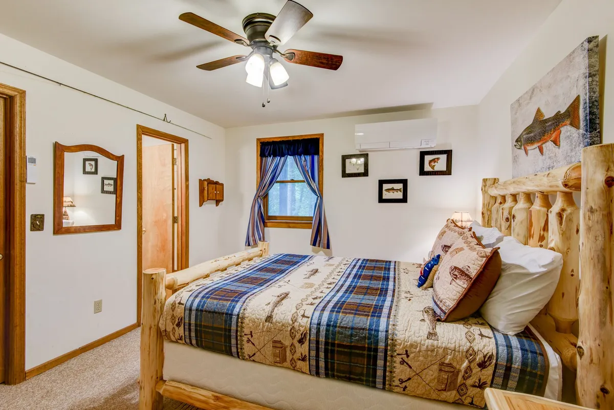 A wooden bed frame with plaid bedding and whimsical fish-themed wall art create a playful yet soothing atmosphere. The window, dressed with curtains, invites soft daylight into the room, enhancing the sense of comfort and retreat.